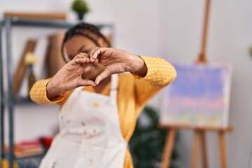 Obraz premium African american woman with braids at art studio smiling in love showing heart symbol and shape with hands. romantic concept.
