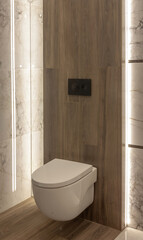 Part of the bathroom with a view of the closed toilet and wood-like tiles on the wall. - 528108014