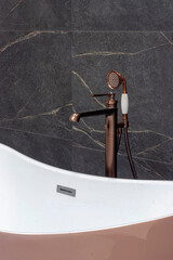 Part of the bathroom with a view of the hand shower, faucet, bathtub and tiles on the wall. - 528108064