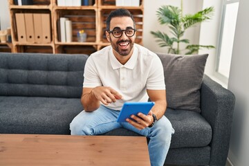 Young hispanic man psychologist having therapy session using touchpad at psychology center