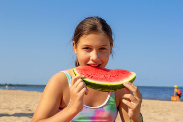joyful children eat watermelon on the beach