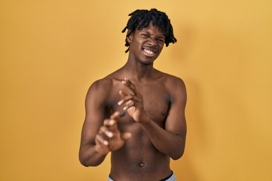 Young african man with dreadlocks standing shirtless disgusted expression, displeased and fearful doing disgust face because aversion reaction. with hands raised