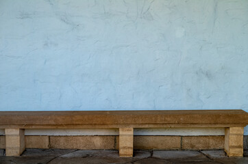 Tan Stone Bench Against a White Stucco Wall.
