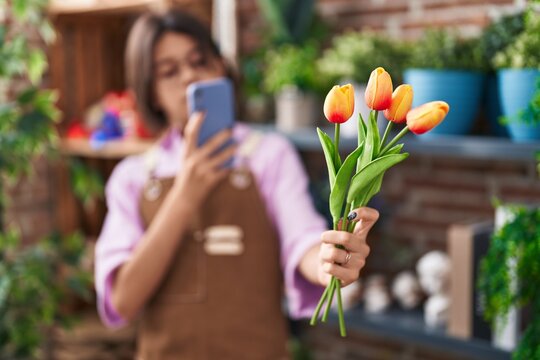Adorable hispanic girl florist make photo to flowers by smartphone at flower shop