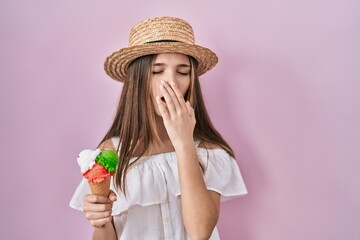 Teenager girl holding ice cream bored yawning tired covering mouth with hand. restless and...