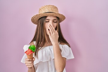 Teenager girl holding ice cream bored yawning tired covering mouth with hand. restless and sleepiness.