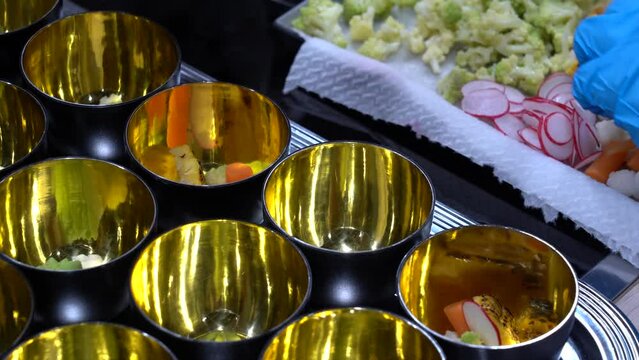 detalle de las manos de unos cocineros con guantes emplatando unos aperitivos.
