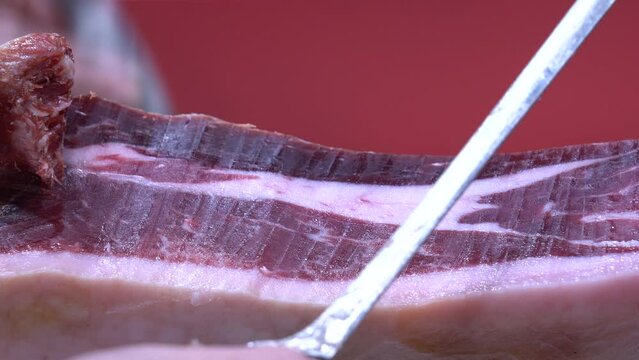 Detalle de las manos de un maestro jamonero cortando tacos de jam&oacute;n. 