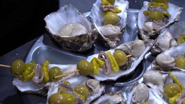 Las manos de un cocinero ali&ntilde;ando unos aperitivos de una receta con ostras.