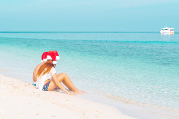 children a boy and a girl in swimsuits and Santa hats stand on the shore of ocean in the Maldives, the concept of holidays and travel in winter and meeting Christmas in the tropics