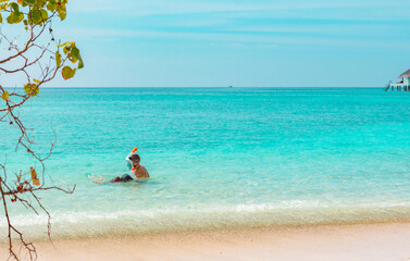 children a boy and a girl swim near the shore in a full face snorkeling mask in Maldives