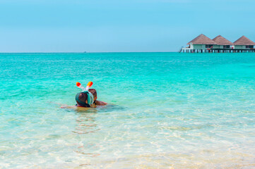 children a boy and a girl swim near the shore in a full face snorkeling mask in Maldives