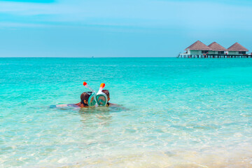 Fototapeta na wymiar children a boy and a girl swim near the shore in a full face snorkeling mask in Maldives