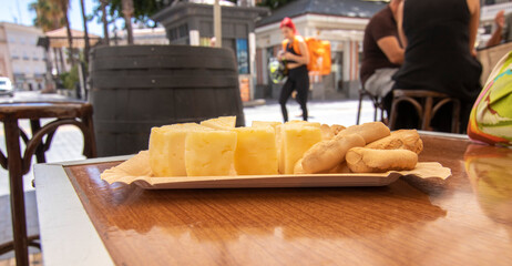 Yellow Portuguese sheep's cheese, cut into pieces and served in a bar outside. Portuguese food concept.