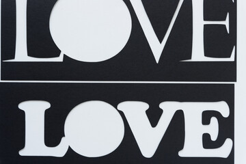 the word love represented with paper (two black paper stencils)