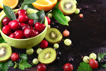 ripe cherry fruit and berries in a bowl of pistachio on dark rust metal background, space for text, horizontal
