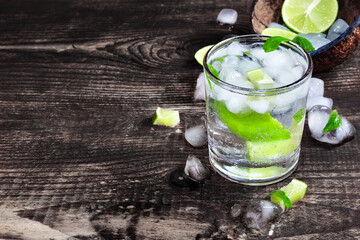 Mojito cocktail on a rustic wooden table, lime, mint, ice cubes and  closeup