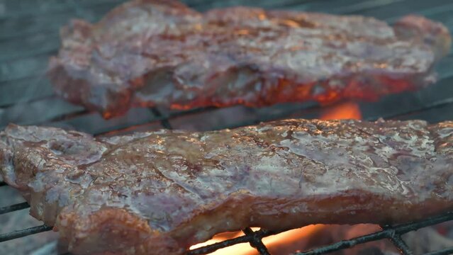 Man cooking and rotating beaf steakes on grill. 4k video footage