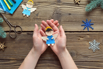 Making handmade christmas angel from felt with your own hands. Childrens DIY concept. Xmas tree decoration, gift, toy or greeting card. Step 4. The finished toy.