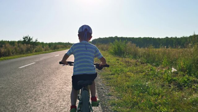 The boy riding his bicycle along the road. 4k video footage 