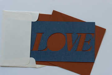 the word love represented with paper (envelope, blue, brown, paper card)