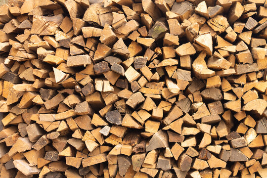 Background of firewood from chopped wood for kindling and heating the house. Woodpile with stacked firewood