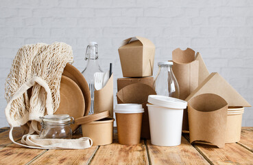 Paper and glass eco-friendly tableware and packaging against a light brick wall. The concept of...