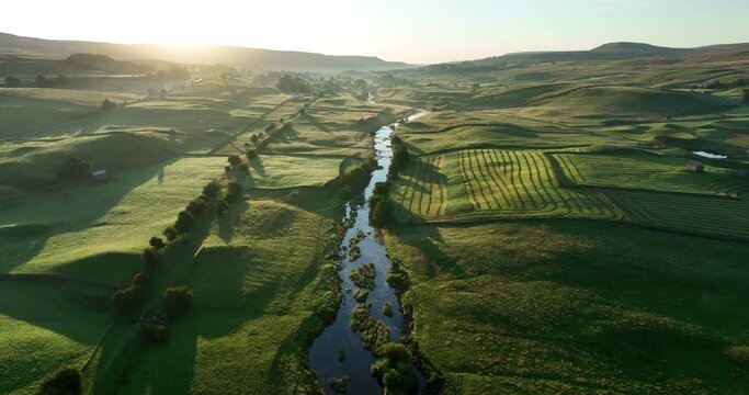 Aerial shot of a still river in a green valley