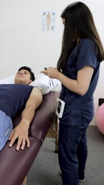 Physical therapist places electrodes on an arm
