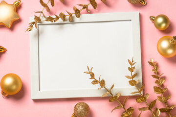 Christmas composition with photo frame and golden christmas decorations at pink background. Flat...