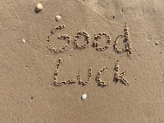 Fototapeta na wymiar on the beach is carved with letters in the smooth sand the writing good luck