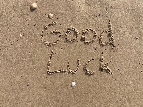 on the beach is carved with letters in the smooth sand the writing good luck
