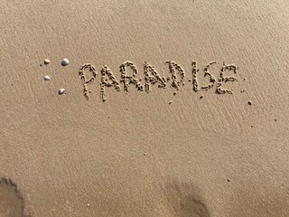 on the beach is carved with letters in the smooth sand the writing paradise