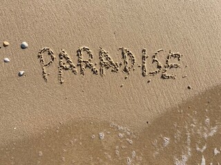 on the beach is carved with letters in the smooth sand the writing paradise