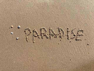 on the beach is carved with letters in the smooth sand the writing paradise