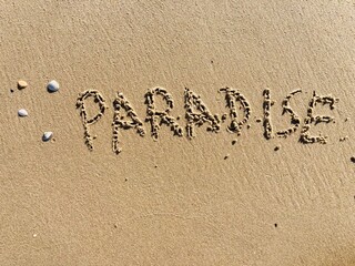 on the beach is carved with letters in the smooth sand the writing paradise