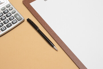 calculator and clipboard on beige background table - office