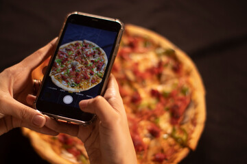 cell phone taking a picture of a pizza