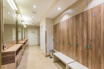 A bright locker room in the wellness center with mirrors and lockers with wooden doors.
