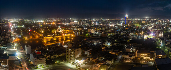Fototapeta na wymiar Panoramic aerial view of Imabari Castle and tower rising above city center at night