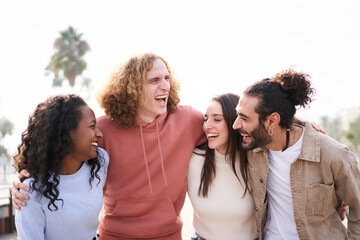 Fototapeta premium Smiling Friends laughing and having fun together. outdoors. Happy multiethnic young group of people hugging together.