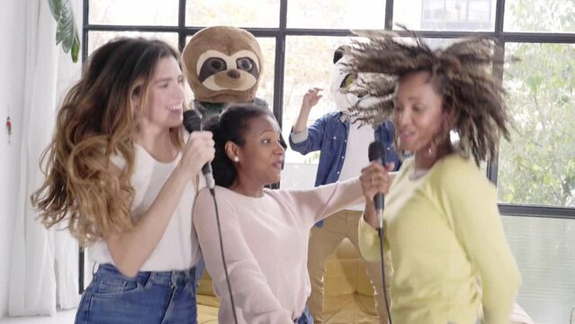 Group of people singing in home karaoke women with animal mask bear panda - Beautiful living room indoors people disguised