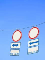 road sign with time information and arrows on blue sky, restricted area, transportation diversity