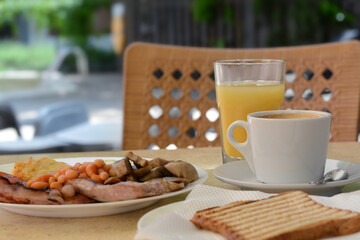 Delicious breakfast with fried meat and vegetables served on beige table in cafe