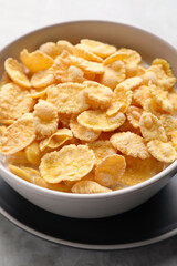 Tasty cornflakes with milk in bowl on table, closeup