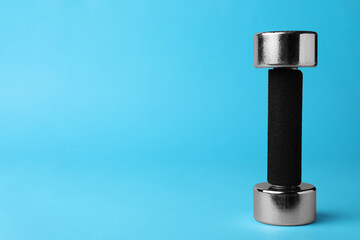 Stylish dumbbell on light blue background, space for text