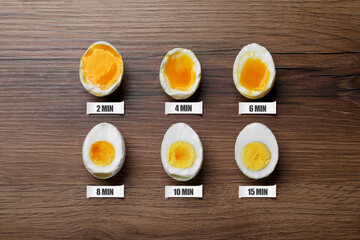 Different readiness stages of boiled chicken eggs on wooden table, flat lay