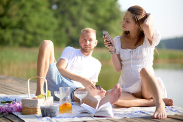 A couple in love are having a picnic in nature by the lake. Hugging, kissing, having a good time. The concept of a happy family.