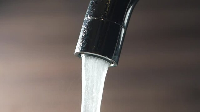 close up of faucet with flowing water 