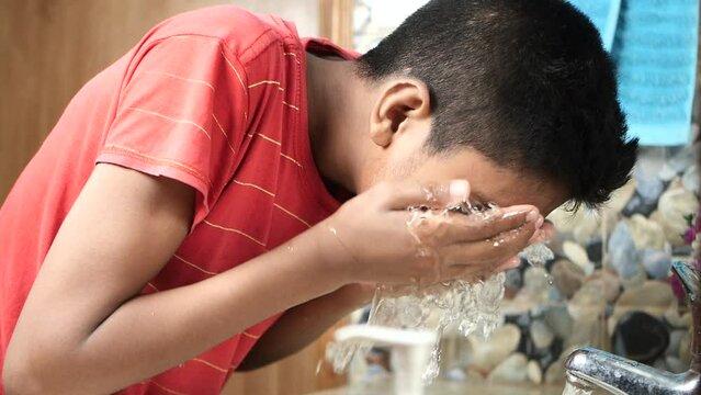 teenage boy cleaning face with a clean water 